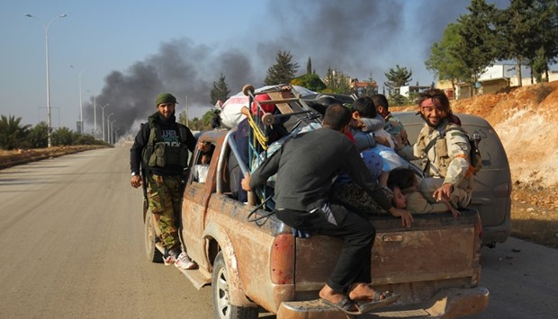 Rebel fighters ride a pick-up truck with civilians who fled areas of conflict in Dahiyet al-Assad, west Aleppo city, Syria