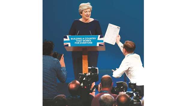 Comedian, Simon Brodkin gives a piece of paper written as a mock P45 (an employee leaving form) to Prime Minister Theresa May as she delivers her speech on the final day of the Conservative Party annual conference at the Manchester Central Convention Centre in Manchester, northwest England, yesterday.