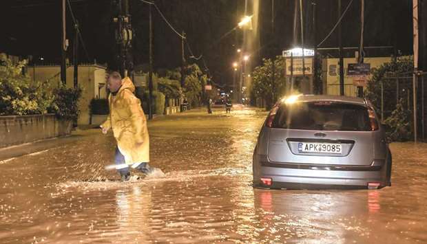 A man walks through flood waters across a road near Corinth during a rain storm late on Saturday.