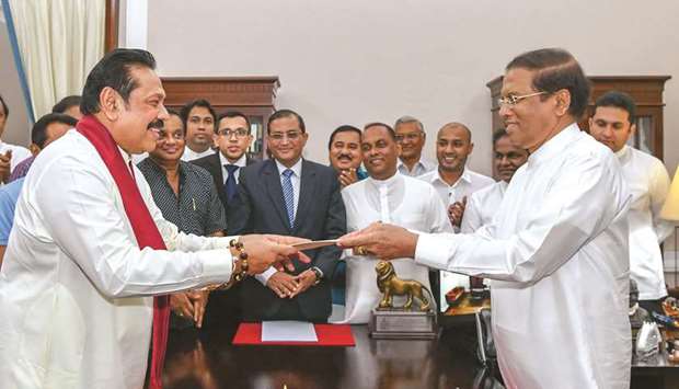 Former Sri Lankan president Mahinda Rajapakse, left, handing over documents to Sri Lankan President Maithripala Sirisena as Rajapakse is sworn in as new prime minister, in Colombo yesterday.