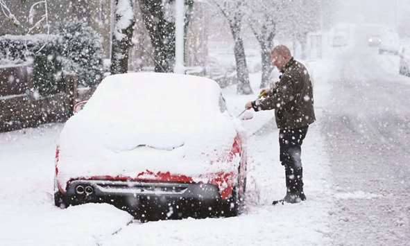 A man clears snow off his car in Greencroft, County Durham.