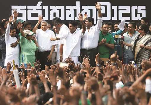 Ranil Wickremesinghe (third left ) waves at his supporters with his party members during a protest against his removal, near the Prime Ministeru2019s official residence in Colombo yesterday.