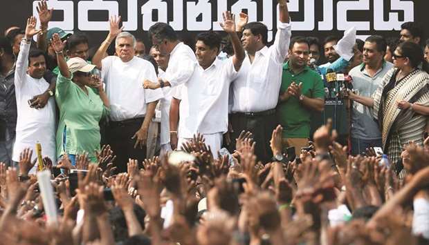 Ranil Wickremesinghe (third left ) waves at his supporters with his party members during a protest against his removal, near the Prime Ministeru2019s official residence in Colombo yesterday.