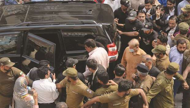 HEARING: Security officials escort Shahbaz Sharif (in a face mask), Pakistanu2019s opposition leader and brother of former prime minister Nawaz Sharif, as he leaves the National Accountability Bureau court after a money-laundering case hearing, in Lahore yesterday.  (AFP)