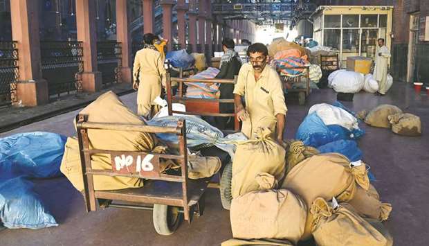 Postal workers sort out sacks containing mail before loading them on a train carriage at a railway station in Lahore yesterday, on World Post Day.