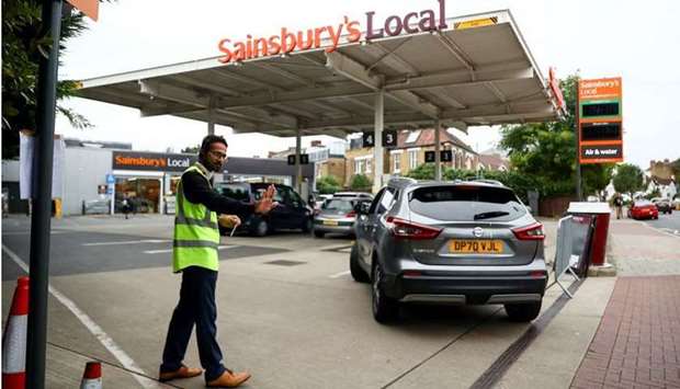 A worker guides vehicles into the forecourt as they queue to refill at a fuel station in London, Britain, on September 30, 2021. (REUTERS)