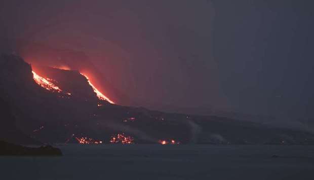 This picture taken from the port of Tazacorte shows the lava of the Cumbre Vieja volcano flowing into the ocean, in the Canary Island of La Palma.