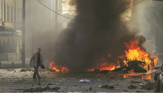 A man is seen near a burned car following a Russian military strike in central Kyiv.