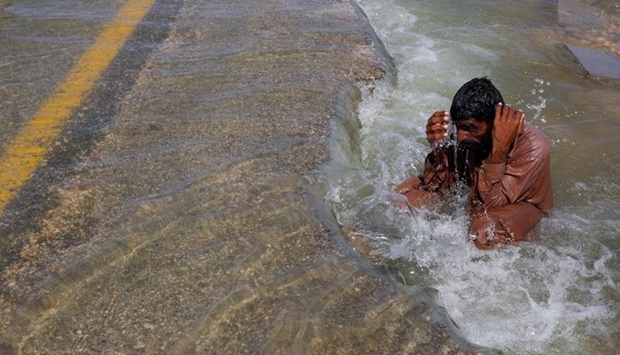 A displaced man cools off to avoid heat on flooded highway, following rains and floods during the monsoon season in Sehwan, Pakistan. (Reuters)