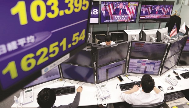 Employees of a foreign exchange trading company work near monitors showing US president-elect Donald Trump speaking on TV news, and the yenu2019s exchange rate against the dollar (left, top) and Nikkei average in Tokyo on November 9.