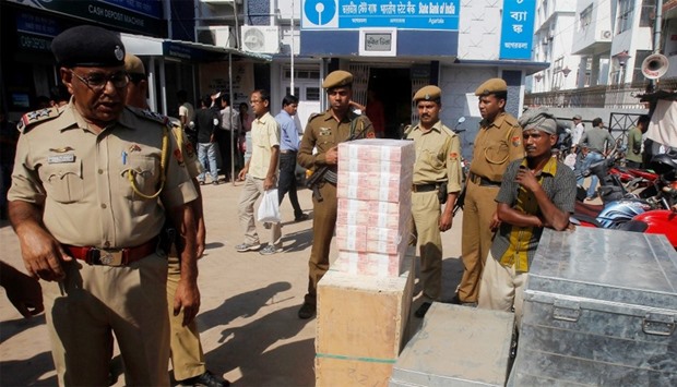 New 2000 Indian rupee banknotes are pictured outside a bank as policemen stand guard