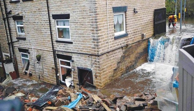 An emergency services worker stands in flood water as he helps to clear the flooding in Stalybridge yesterday.