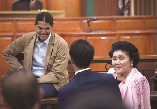 Former First Lady Imelda Marcos talks to her grandson after taking the witness stand in the anti-corruption court Sandiganbayan in Quezon City, Metro Manila, on Friday.