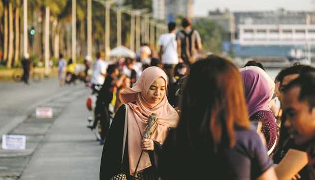 People sit along a sea wall of Manila Bay in Manila (file). The Philippine government is currently working on a legislation for the development of Islamic finance and a framework that would allow the country to set up more Islamic banks, reach out to its underbanked 10mn-plus Muslim community and issue government and corporate Islamic bonds, or sukuk.