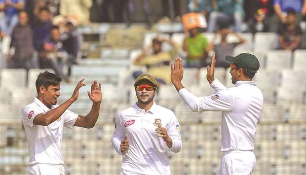 Bangladeshu2019s Taijul Islam (left) celebrates with captain Shakib Al Hasan (centre) and another teammate after the dismissal of West Indiesu2019 Devendra Bishoo on the third day of the first Test at the Zahur Ahmed Chowdhury Stadium in Chittagong on Saturday. (AFP)