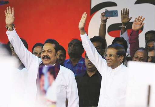 Sri Lankau2019s former president and newly appointed prime minister Mahinda Rajapakse, left, and President Maithripala Sirisena wave to supporters at a rally in Colombo yesterday.