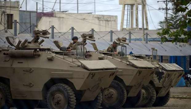 Soldiers remain inside armoured vehicles outside the Guayas 1 prison in Guayaquil, Ecuador, yesterday, after a riot occurred.  AFP