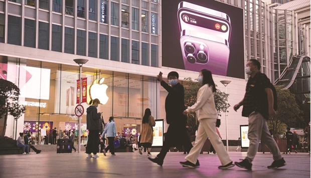 People walk near a display advertising the Apple iPhone 14 outside its store in Shanghai yesterday. Apple Inc said it expects lower-than-anticipated shipments of high-end iPhone 14 models following a key production cut at the virus-blighted Zhengzhou plant.