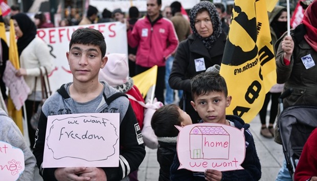 Children carry signs as migrants and refugees demonstrate in Athens on January 21, 2017, in solidarity with the Women's March on Washington, one day after the inauguration of Donald Trump as US President