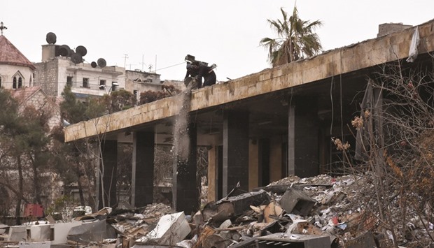 Syrian workers remove rubble from a rooftop as they clean up the water station in Aleppou2019s Suleiman al-Halabi neighbourhood.