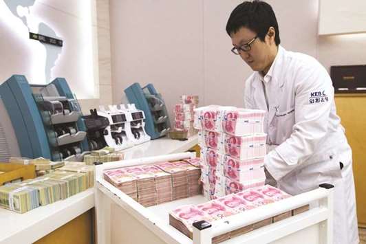 An employee arranges yuan banknotes at the Korea Exchange Bank headquarters in Seoul (file). The Chinese currency has surged last year amid tighter capital controls, climbing bond yields and a slump in the dollar.