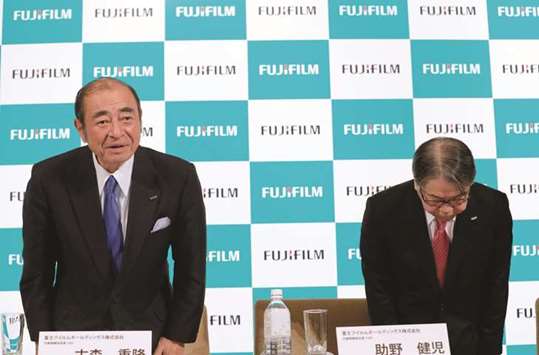 Fujifilm Holdingsu2019 chief executive officer Shigetaka Komori (left) and chief operating officer Kenji Sukeno greet attendees after their news conference in Tokyo yesterday. Fujifilm yesterday reported a 29.4% drop in operating profit at its document solutions operations, which includes Fuji Xerox, for the third quarter, underperforming its imaging and information segments.