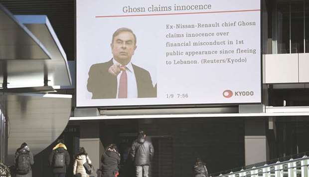 Pedestrians walk past a screen displaying a news broadcast on former Nissan Motor Co chairman Carlos Ghosn in Tokyo on Thursday. Ghosn was once celebrated for rescuing Nissan from ruin two decades ago, earning him accolades as one of the Japanu2019s most revered corporate leaders. But for many in the country now, his 2018 detention and allegations of financial crimes fostered the impression that he lost his management magic, got greedy, and most importantly for a nation that prides itself on law and order u2014 broke the rules.
