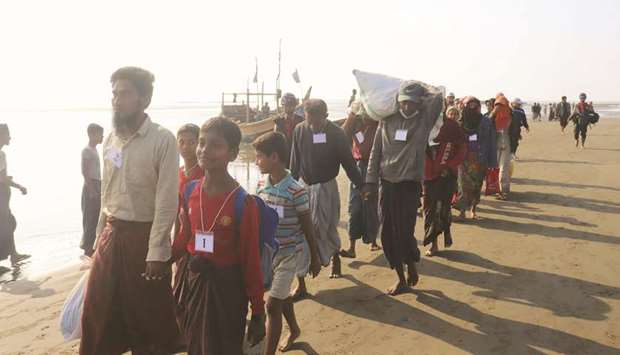 Rohingya people who were arrested at sea in December walk on a beach after being transported by Myanmar authorities to Thalchaung near Sittwe in Rakhine state yesterday.