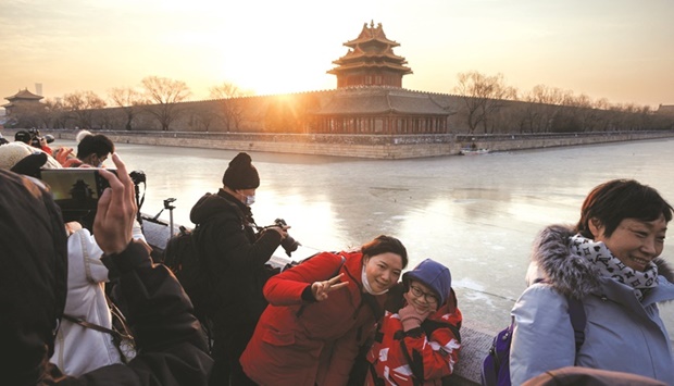 People pose for pictures as the first sun of the year rises above the Forbidden City in Beijing as the city prepares to host the Winter Olympics.