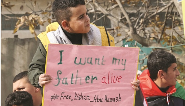 Palestinian hunger-striking prisoner Hisham Abu Hawashu2019s son Ezzeddin lifts a placard during a rally in his village of Dura, west of Hebron in the occupied West Bank, yesterday to demand his release from Israeli detention.