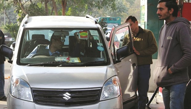 A man applies CNG sticker on a car at a refill station in New Delhi yesterday.