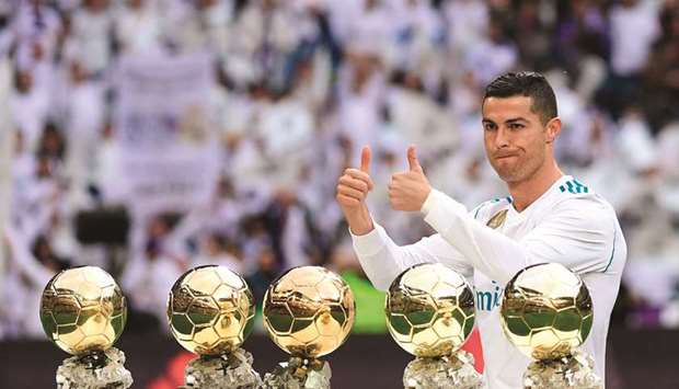 Real Madridu2019s Portuguese forward Cristiano Ronaldo poses with his five Ballon du2019Or trophies ahead of the Spanish league football match between Real Madrid and Sevilla at the Santiago Bernabeu Stadium in Madrid yesterday.