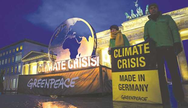 Greenpeace activists stand near to a giant globe installation erected in front of Berlinu2019s Brandenburg Gate yesterday.