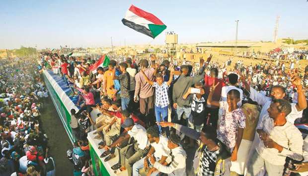 Sudanese protesters cheer upon arriving from the capital Khartoum to the town of Atbara yesterday to celebrate the first anniversary of the uprising that toppled Omar al-Bashir and to demand justice for slain protesters.