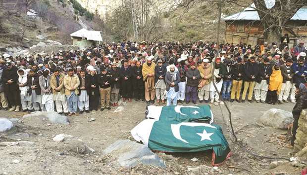 People stand in front of coffins draped in Pakistanu2019s national flags during the funeral of the victims who, according to local media, were killed in cross-border shelling, in Lesva village in Neelum Valley, Pakistan.