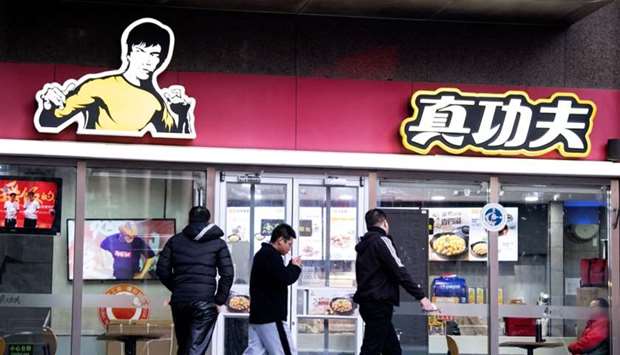 People walk past the restaurant Real Kung Fu, or Zhen Gongfu in Mandarin, run by fast food chain Kungfu Catering Management, in Beijing