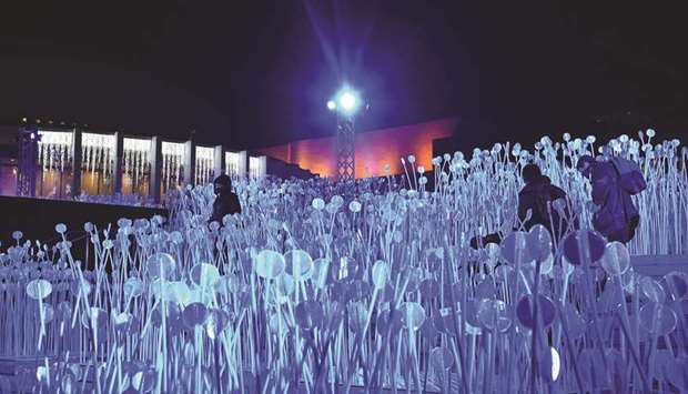 People explore the u2018Entre les rangsu2019 comprising thousands of flexible stems topped with white reflectors. This installation reinterprets a slice of Quebecu2019s agricultural history, and is one of the five light installations on display to bring some comfort to residents of a city that has been battered by months of coronavirus in Montreal, Quebec. (AFP)