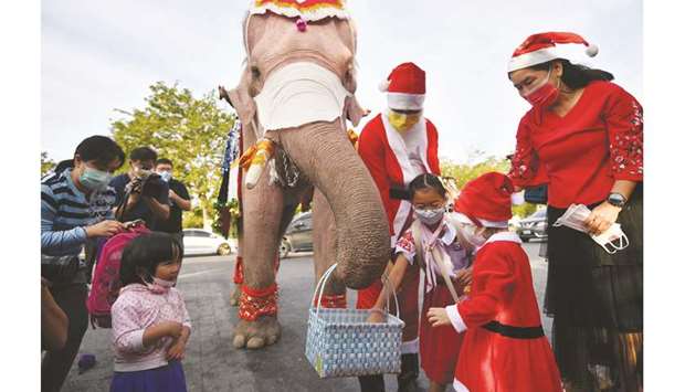 Students receive face masks from an elephant dressed as Santa Claus, in an effort to help prevent the spread of the coronavirus disease (Covid-19), ahead of Christmas celebrations at a school in Ayutthaya, yesterday.