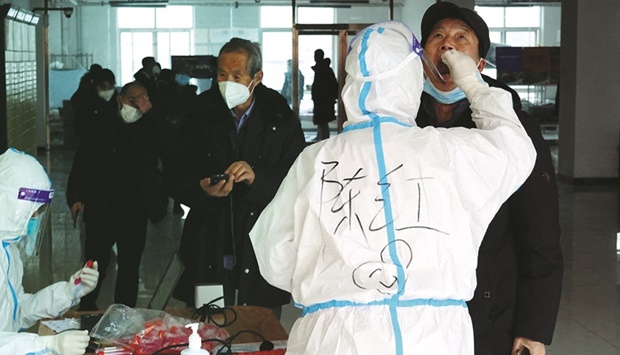 A medical worker in protective suit collects a swab sample from a man for nucleic acid testing at a residential compound, during another round of mass testing following the Covid-19 outbreak in Xian, Shaanxi province, China.