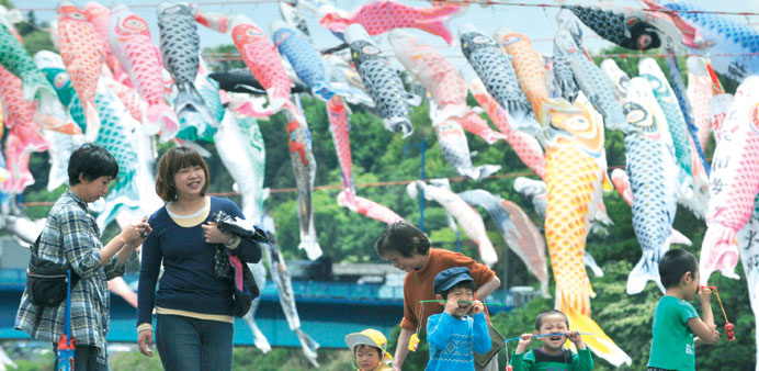 A family walks beside colourful carp streamers flying above a riverside park in Sagamihara, Kanagawa prefecture yesterday to celebrate Childrenu2019s Day.