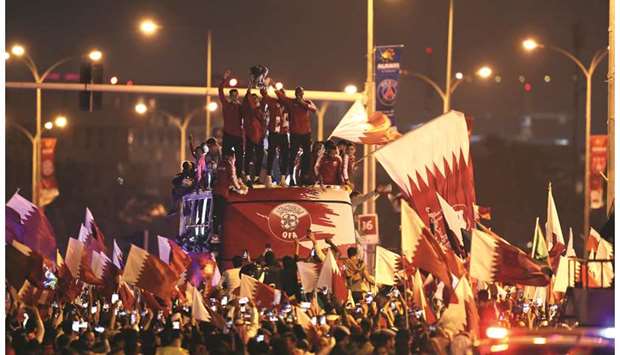 Qatar players and officials hoist the AFC Asian Cup trophy during a victory parade in Doha yesterday. (Reuters)