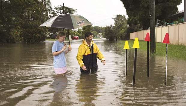 Local resident Paul Shafer and his daughter Lily stand in floodwaters near star pickets that show where the storm water cover has been removed in Hermit Park, Townsville, northern Queensland, yesterday.