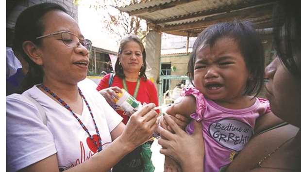 Community health nurse Mylene Pontanos injects a measles vaccine to a child in Barangay Payatas.