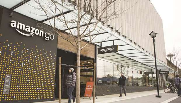 Pedestrians walk by Amazon.comu2019s new Amazon Go grocery store, located adjacent to the Amazon.com headquarters in Seattle. Amazon is betting a frictionless checkout experience will help it grab a bigger share of the $800bn US grocery market, now dominated by Walmart.