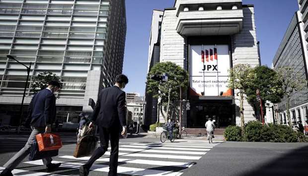 Pedestrians cross a road in front of the Tokyo Stock Exchange. Japan Exchange Group, which owns the bourse, plans to cut the number of market segments, apply new listing criteria and turn five confusing, overlapping divisions into three simpler sections: Blue-chips, start-ups, and the rest.