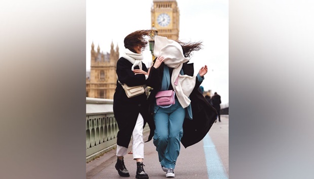 People struggle in the wind as they walk across Westminster Bridge, near the Houses of Parliament in central London, yesterday as Storm Eunice brings high winds across the country.