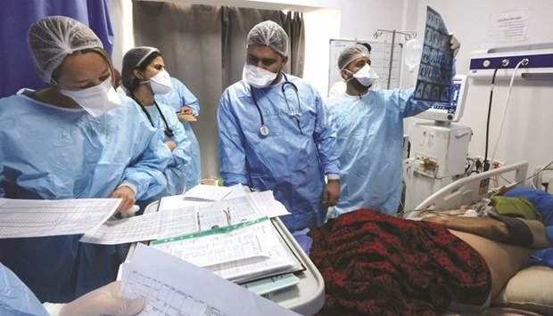 Iraqi medical workers check on a patient at the coronavirus ward of Al-Shifa  Hospital in the capital Baghdad.