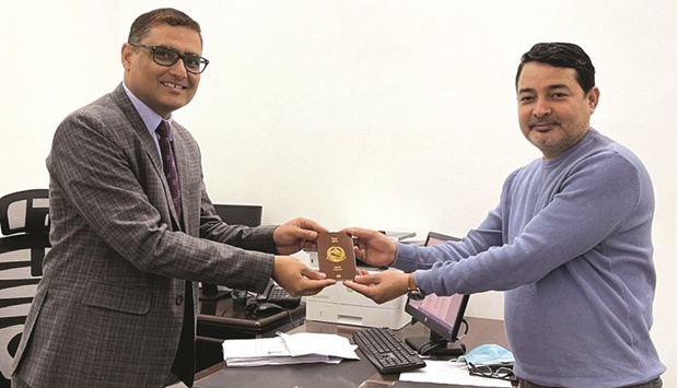 Nepal embassy charge d'affaires Lakshuman Khanal handing over a new e-passport to an applicant.