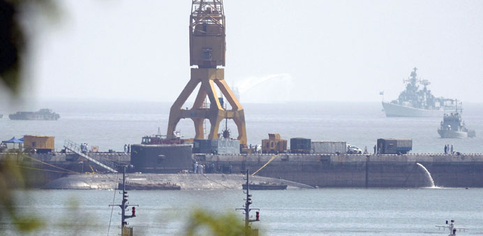 A navy submarine, believed to be the Russian-built INS Sindhuratna, is seen anchored at the naval dockyard as a fire truck (partially obscured) and su