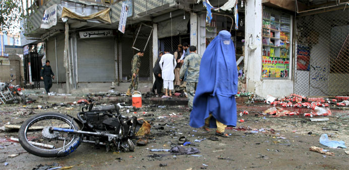 An Afghan woman walks at the site of a suicide attack in Jalalabad 